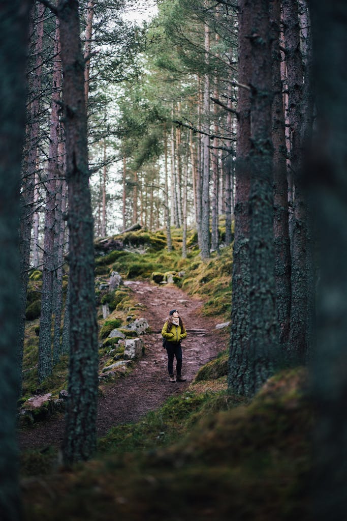 A woman enjoys a scenic hike through a wooded pathway in Balmoral, Scotland.