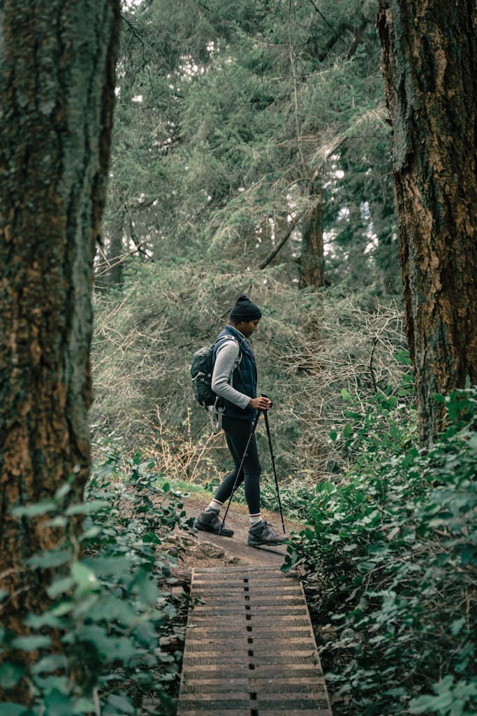 Black woman hiking through a dense forest trail, enjoying nature and outdoor adventure.